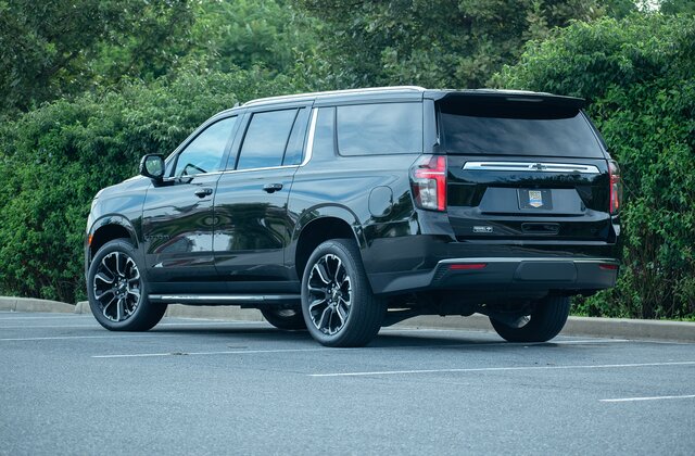 Rear view of a black luxury SUV used for limo service Santa Barbara, parked in an outdoor lot with surrounding greenery.